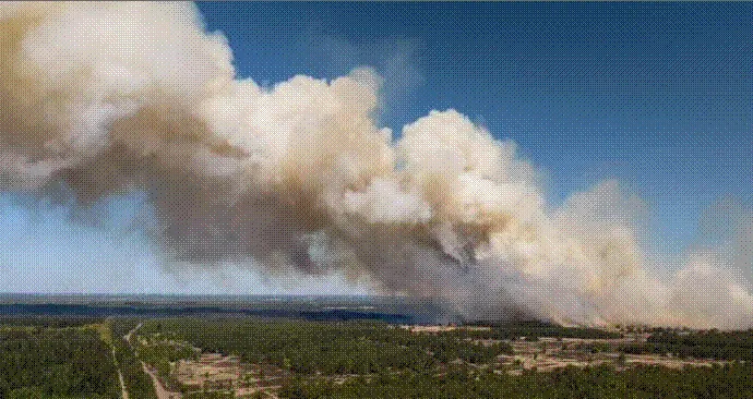 Grote rookpluim van een natuurbrand boven open heideterrein, gezien vanuit de lucht